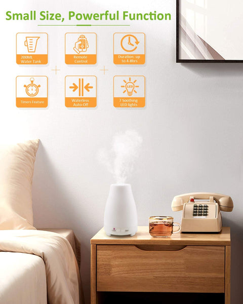 AIMASON essential oil diffuser, which is small but powerful. It is placed on a table with mist spraying from it, beside the bed, alongside a telephone and glass of tea on the wooden table