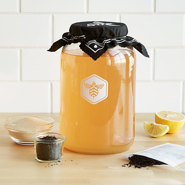 yellow kombucha brew in a glass with a black cloth on top